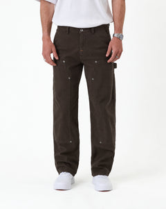 The Carpenter Pant in brown — front view with white sneakers