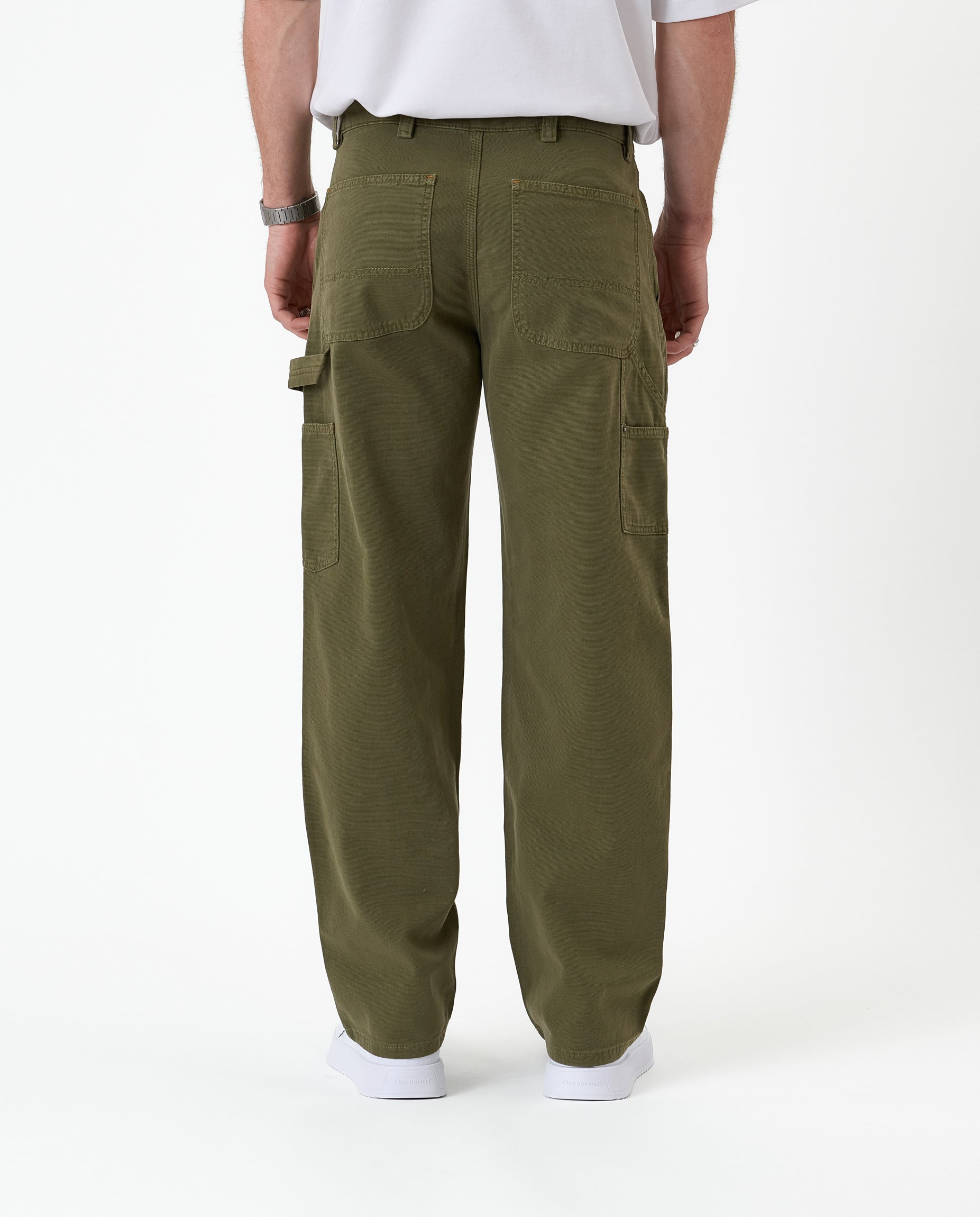 The Carpenter Pant in olive green — back view showing utility pockets and a hammer loop