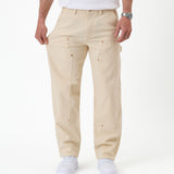 The Carpenter Pant in sand — pulled at the thigh to demonstrate the stretch fabric