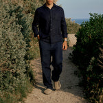 The Daily Linen Trouser in navy — worn while walking on a dirt path outdoors