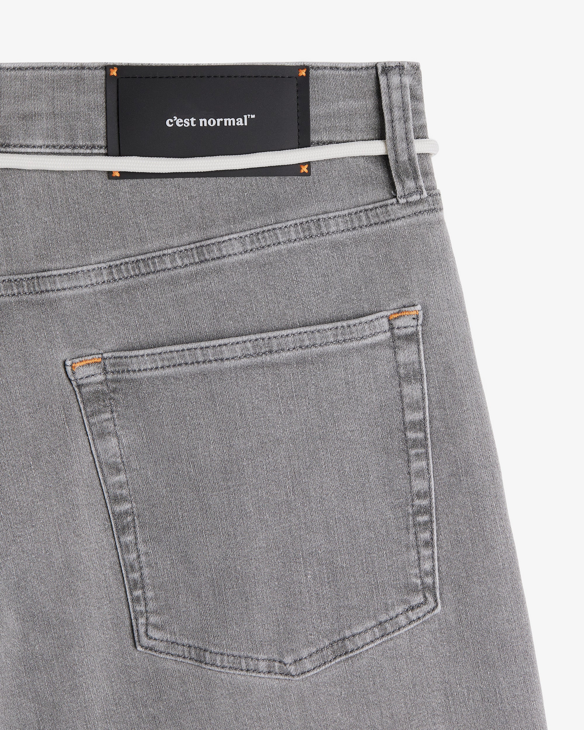 The Jeans Relaxed Straight Fit in light grey — close-up of the back waist with a rubber patch and C'est normal logo