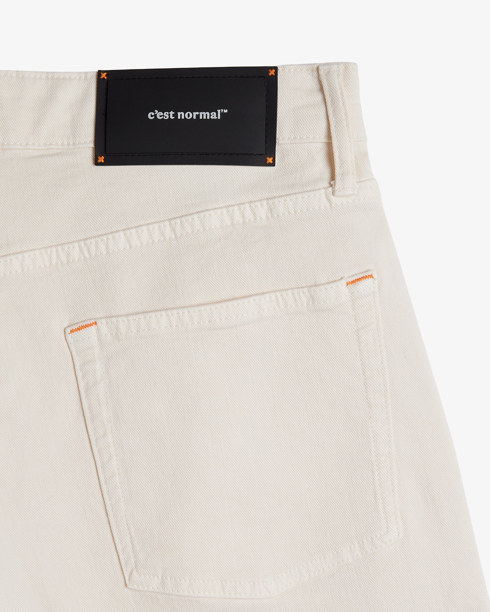 The Jeans Relaxed Straight Fit in ecru — back pocket with a black C'est normal rubber patch