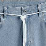 The Jeans Relaxed Straight Fit in light blue — closeup of the waist with branded hardware and a white cord belt