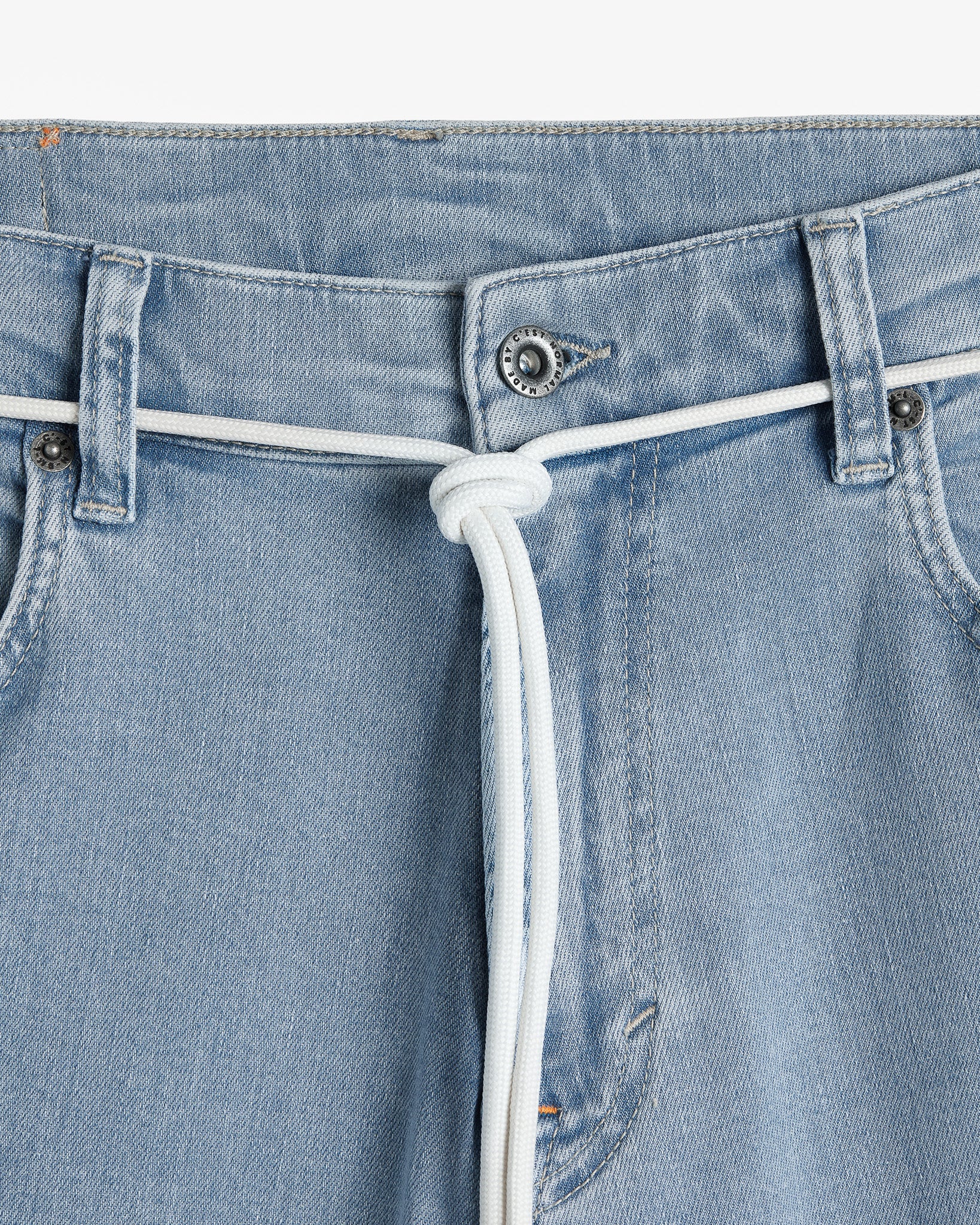 The Jeans Relaxed Straight Fit in light blue — closeup of the waist with branded hardware and a white cord belt