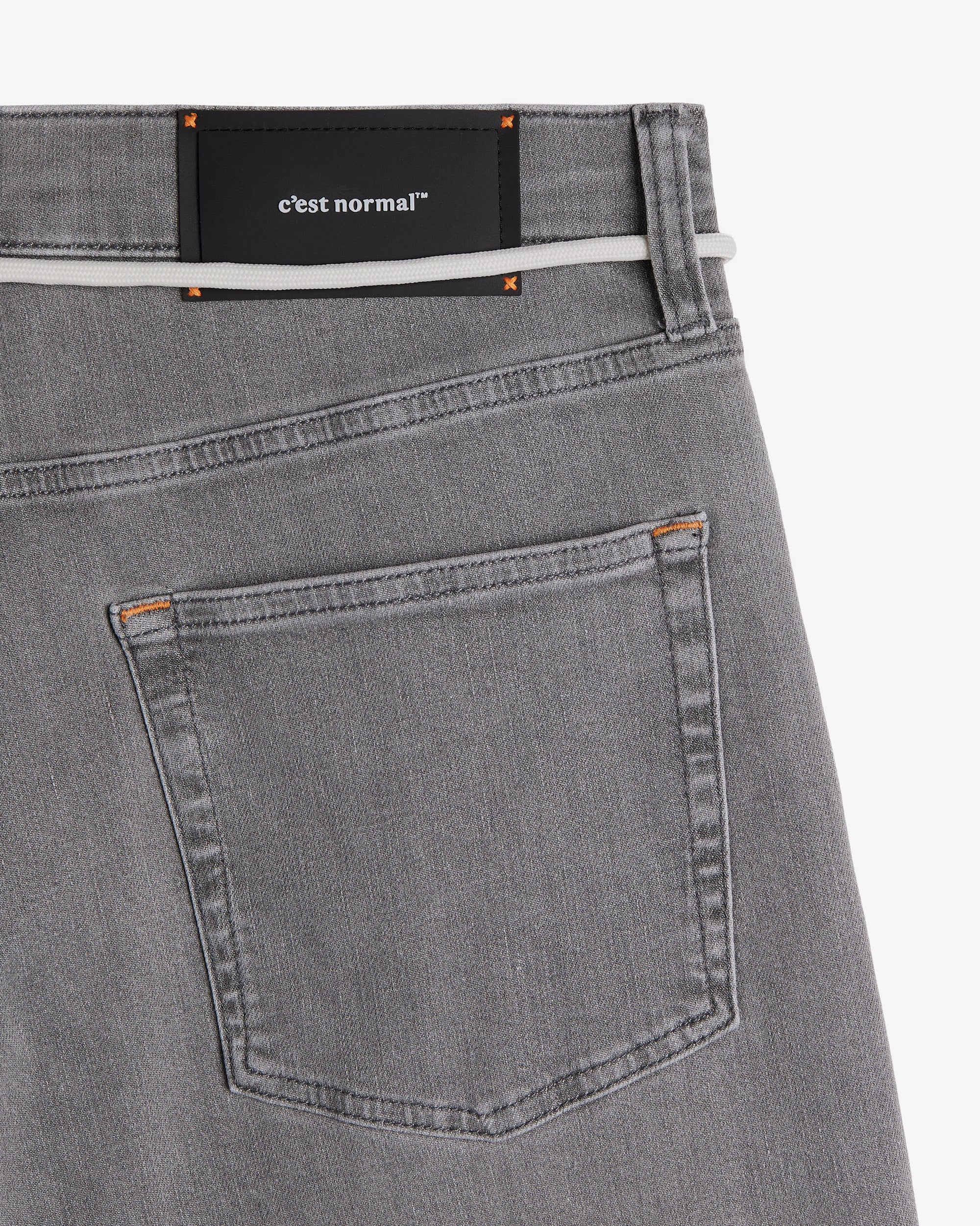 The Jeans Relaxed Straight Fit in light grey — back pocket and black C'est normal rubber patch