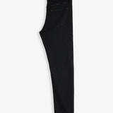 The Jeans Slim Fit in Jet Black, folded in half and laid flat on a white background. The image highlights the back pocket, subtle orange accent stitching, and the rubber patch with the c'est normal logo at the back waist.