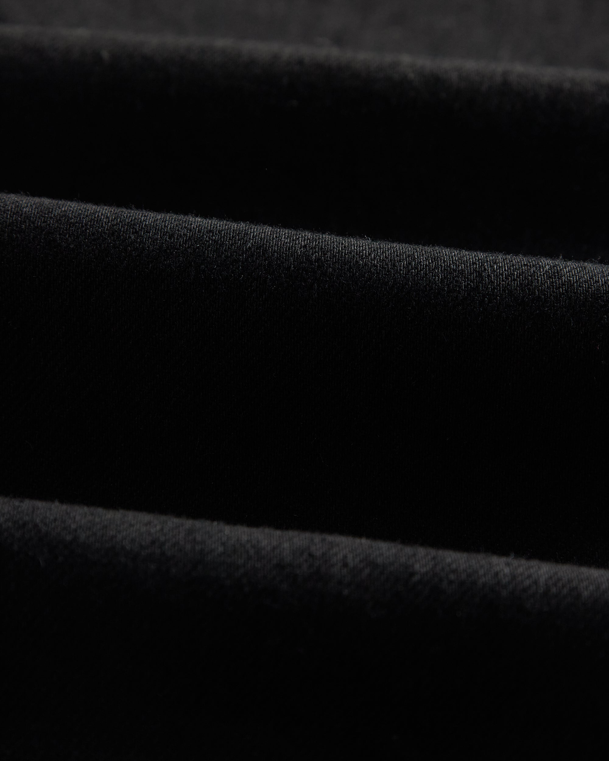 A close-up shot of the jet black Motion Fabric of The Jeans Slim Fit by c'est normal, highlighting its texture.