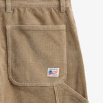 The Lille Cord Carpenter Pant in dark sand — close-up of the back pocket and logo label