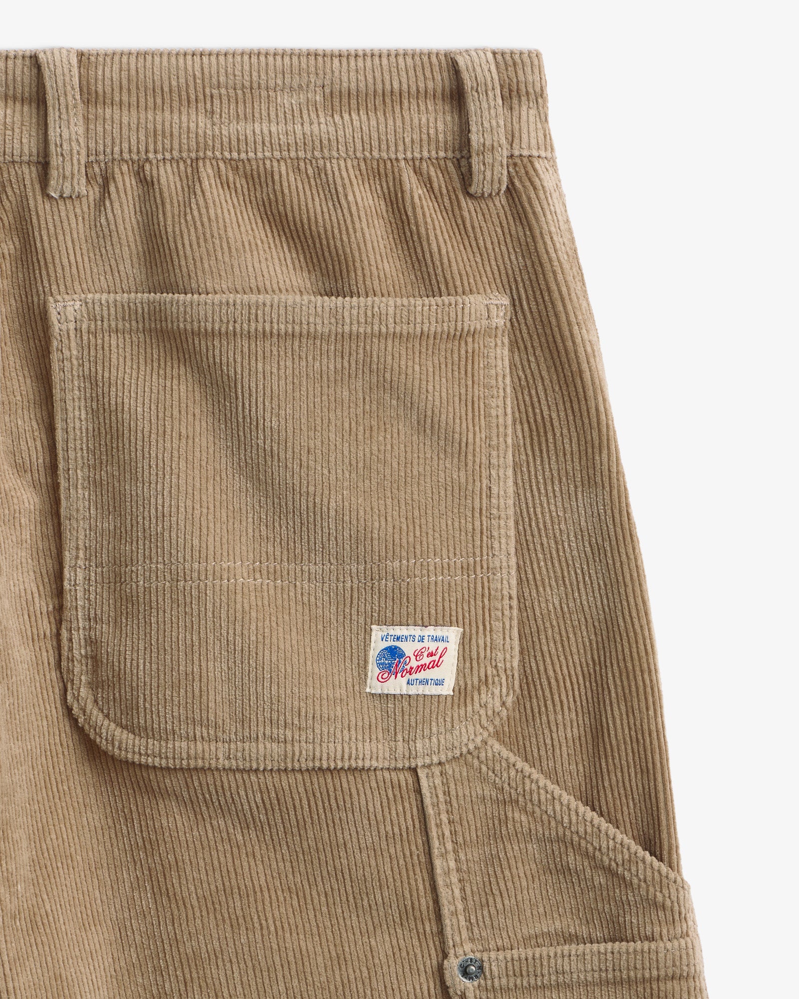 The Lille Cord Carpenter Pant in dark sand — close-up of the back pocket and logo label
