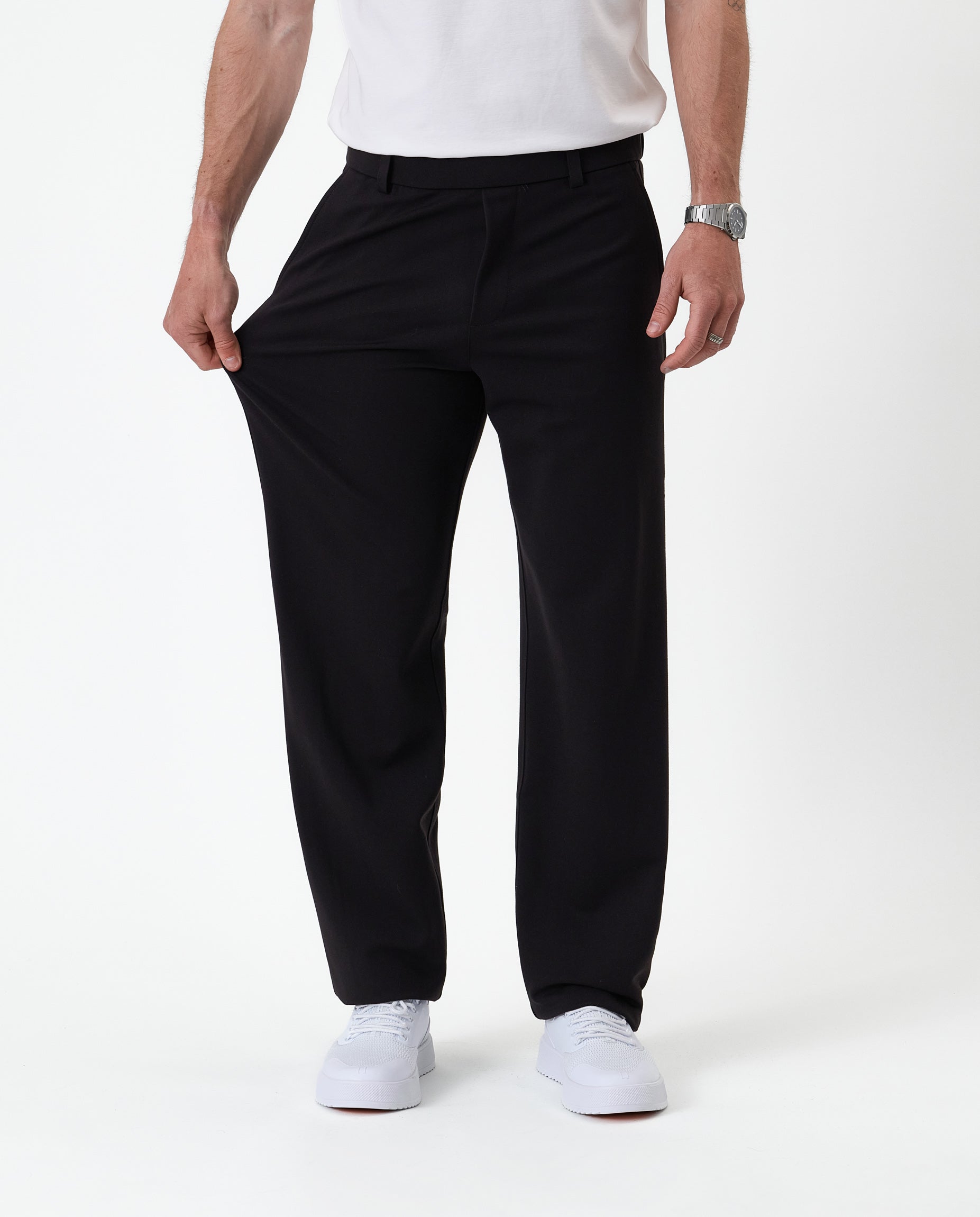 The Proper Pant Relaxed Straight Fit in black — pulling the fabric to show the stretch