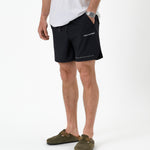 The Shorts in black — worn with olive green clogs and a white t-shirt