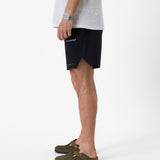 The Shorts in black — side view showing the notched hem and white C'est normal logo
