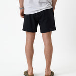The Shorts in black — back view worn with a white t-shirt and olive sandals