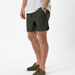 The Shorts in khaki — front view showing the side logo and hand in pocket