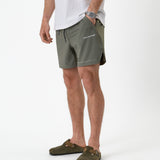 The Shorts in mulled green — side view showing the white logo and notched hem