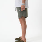 The Shorts in mulled green — side view showing the notched hem and C'est normal logo