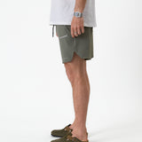 The Shorts in mulled green — side view showing the notched hem and C'est normal logo