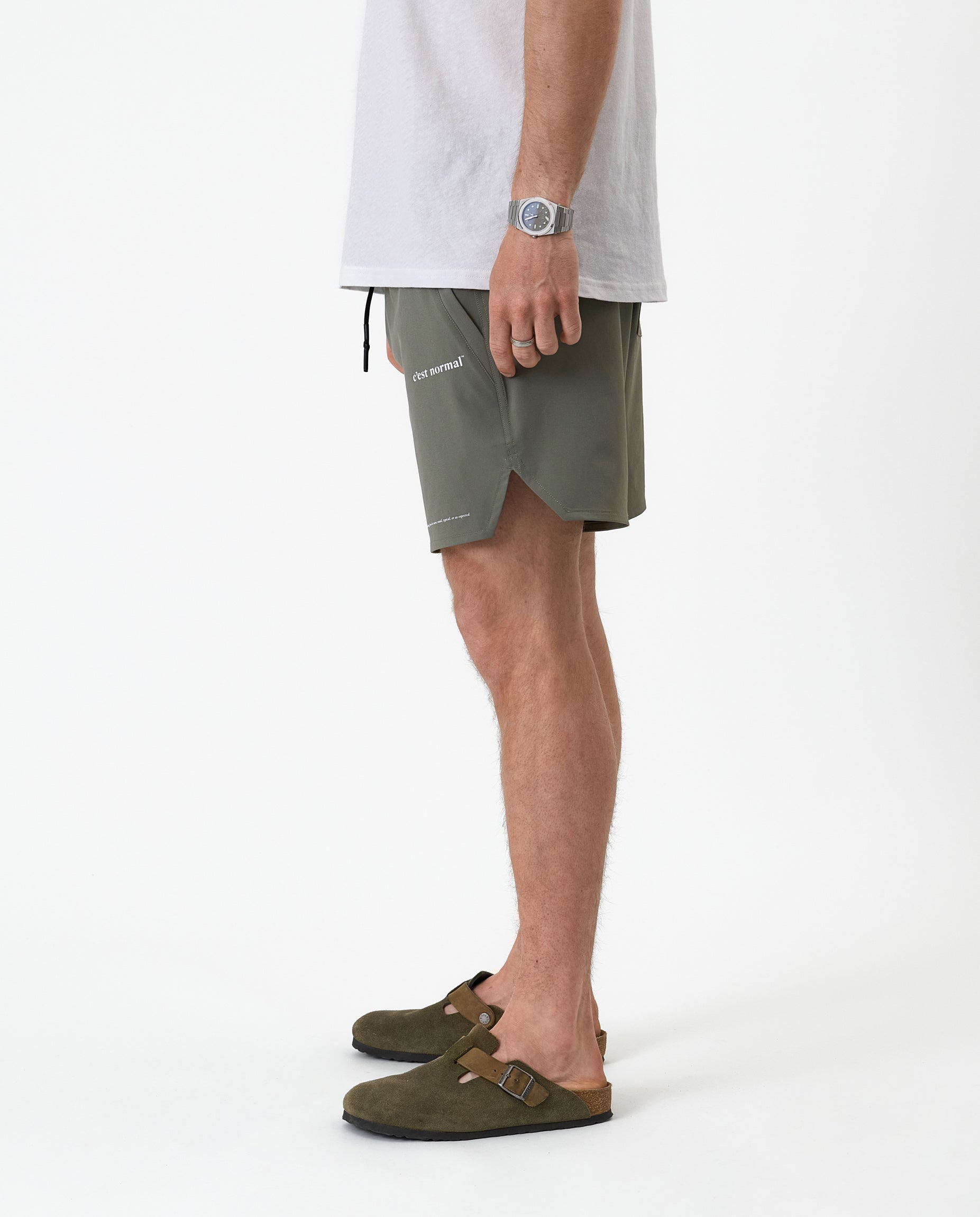 The Shorts in mulled green — side view showing the notched hem and C'est normal logo