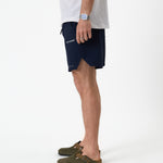 The Shorts in navy — side profile showing the notched hem and C'est normal logo