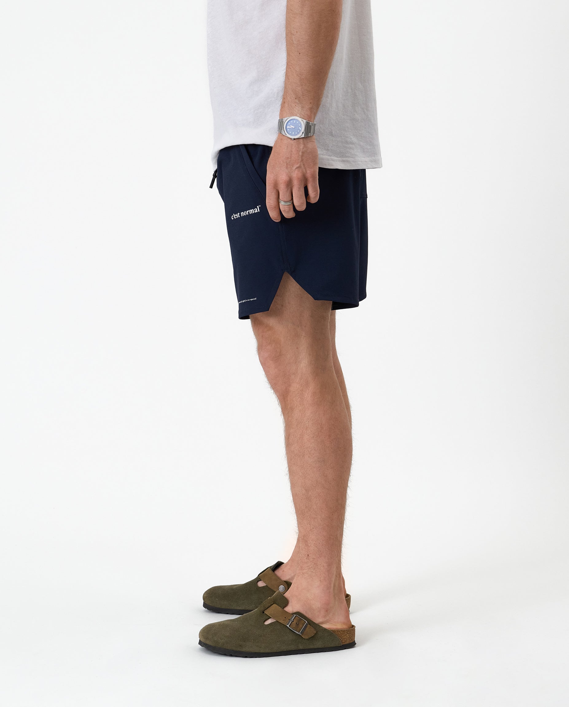 The Shorts in navy — side profile showing the notched hem and C'est normal logo