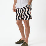 The Shorts in Noir Curl Stripe — worn with a white t-shirt and olive green clogs