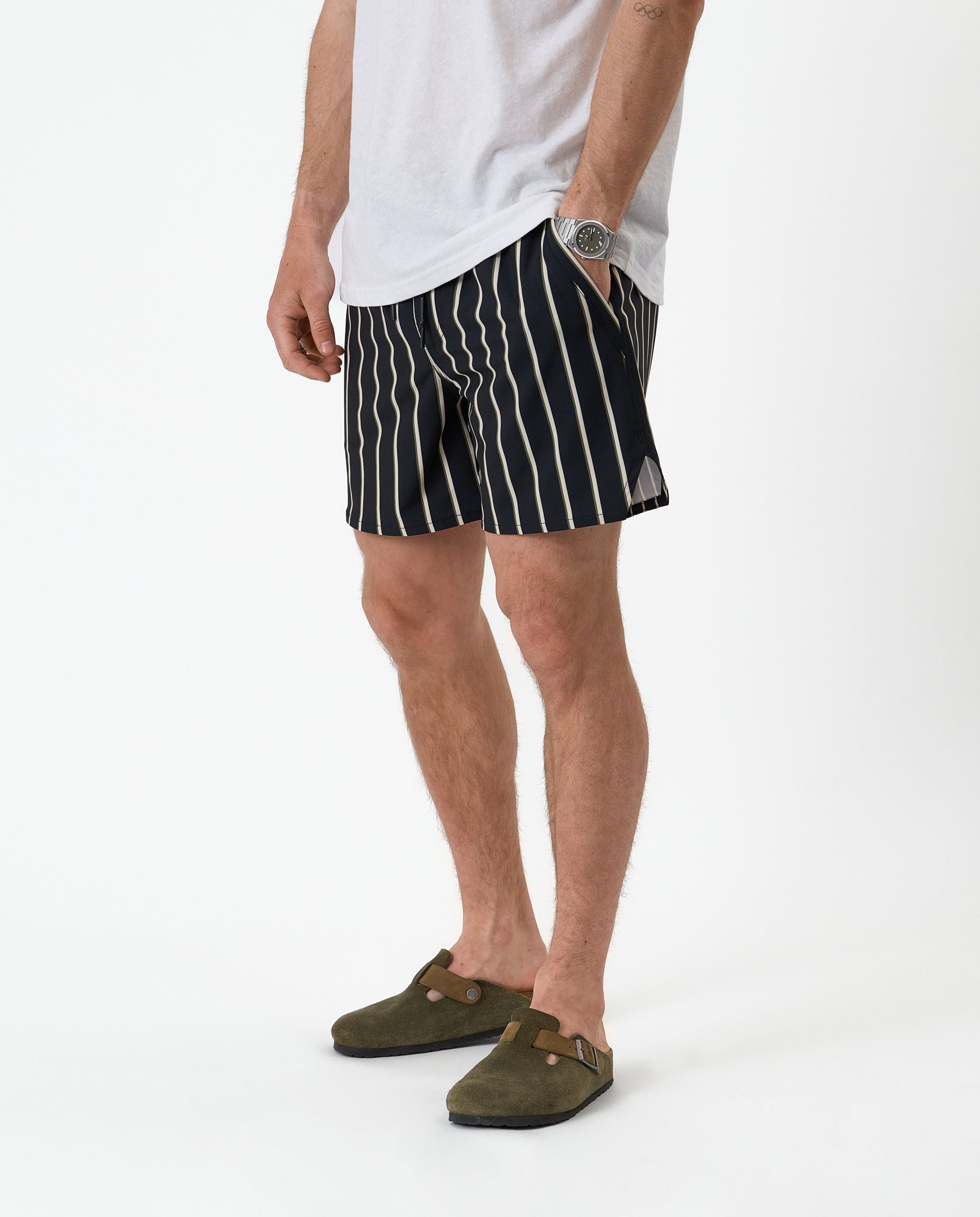 The Shorts in noir stripe — worn with a white t-shirt and olive green clogs