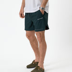 The Shorts in pine — worn with olive green clogs and a white t-shirt