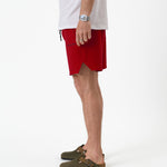 The Shorts in red — side view showing the notched hem and C'est normal logo
