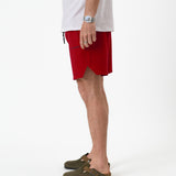 The Shorts in red — side view showing the notched hem and C'est normal logo
