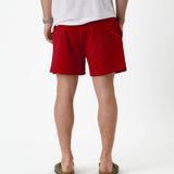The Shorts in red — back view worn with a white t-shirt and olive sandals
