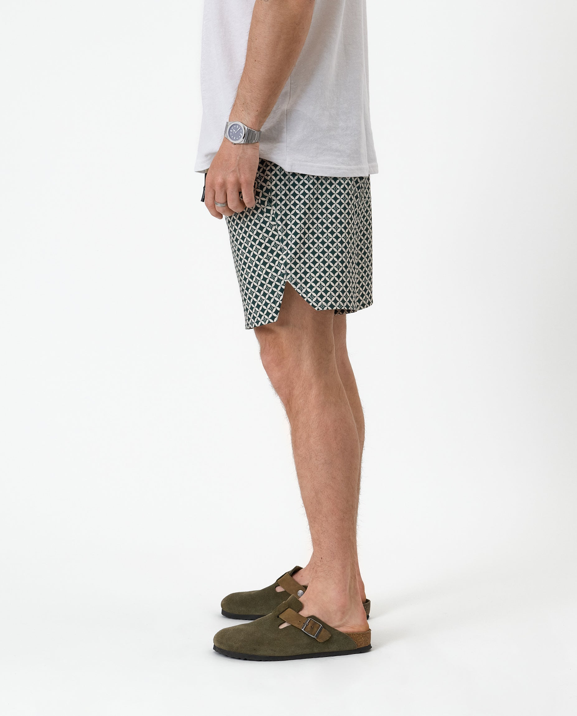The Shorts in tile — side profile showing the notched hem and green suede clogs