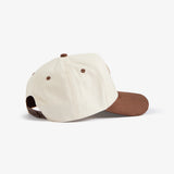 A side and back view of The Snapback Cap in cream and brown, placed on a white background. The image highlights the cream crown, brown brim, brown eyelets, and brown adjustable snapback closure.