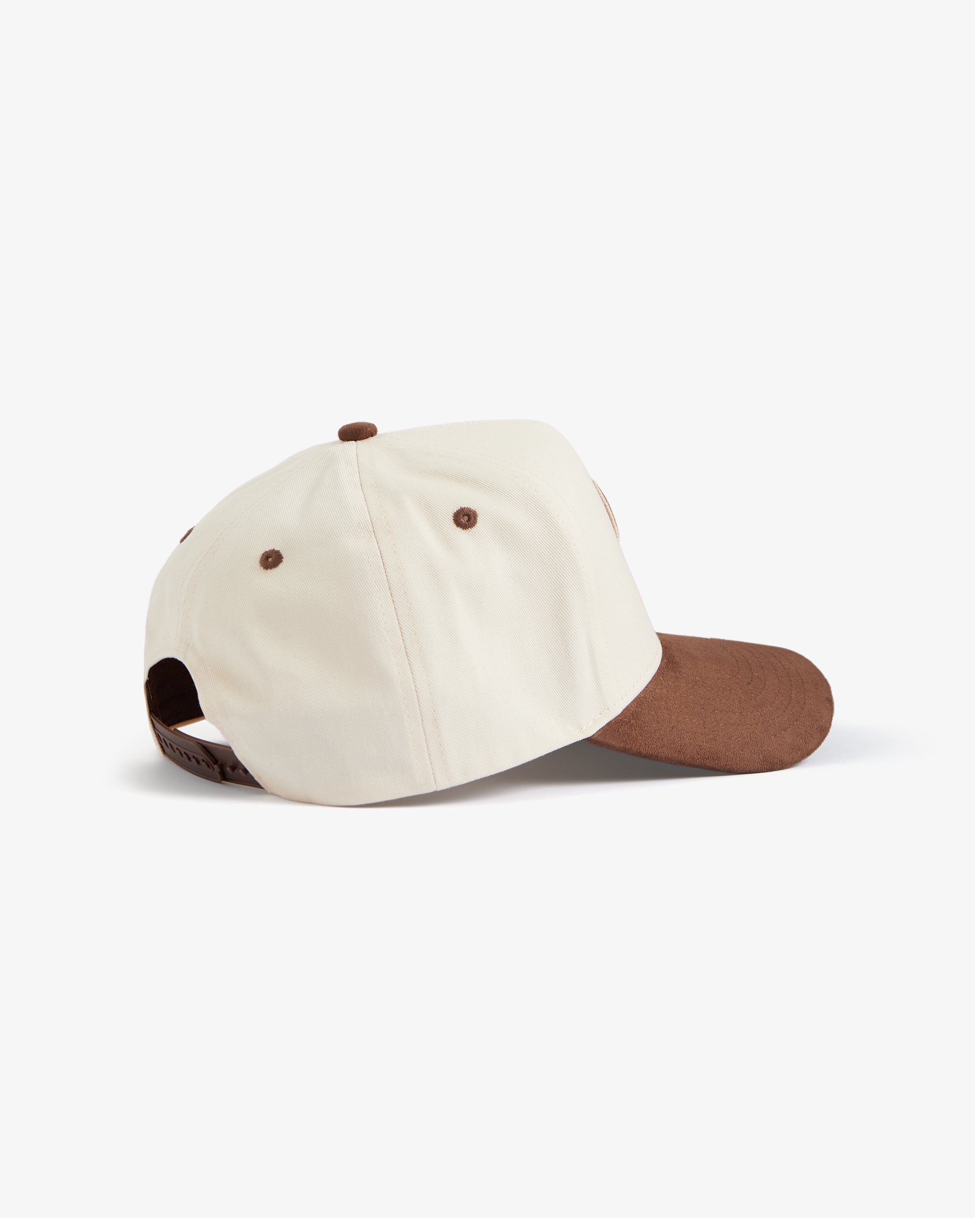 A side and back view of The Snapback Cap in cream and brown, placed on a white background. The image highlights the cream crown, brown brim, brown eyelets, and brown adjustable snapback closure.