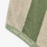 The Lombok Beach Towel in Lombok Stripe — showing the cotton texture and C'est normal logo