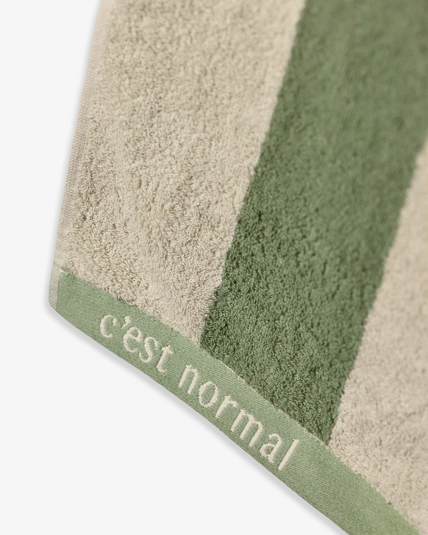The Lombok Beach Towel in Lombok Stripe — showing the cotton texture and C'est normal logo