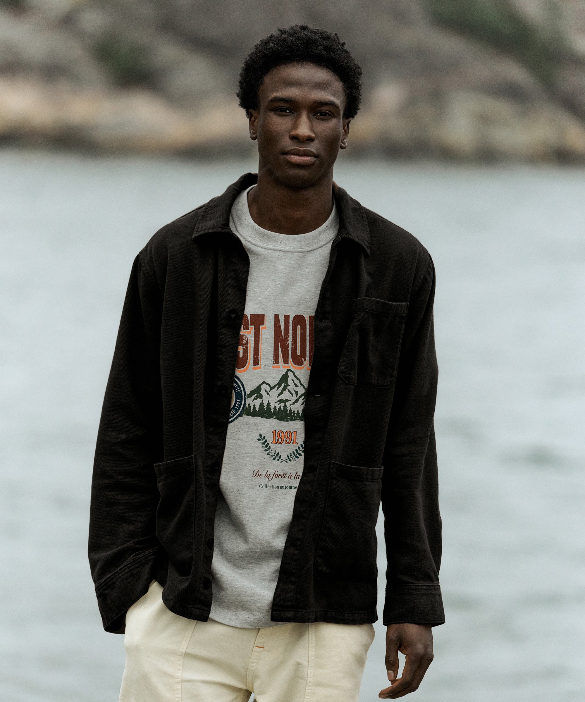 The Workwear Overshirt in black — worn over a C'est normal graphic t-shirt