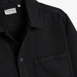 The Workwear Overshirt in black — close-up of the collar and chest pocket with subtle branding