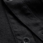 The Workwear Overshirt in black — close-up of the buttons engraved with C'est normal