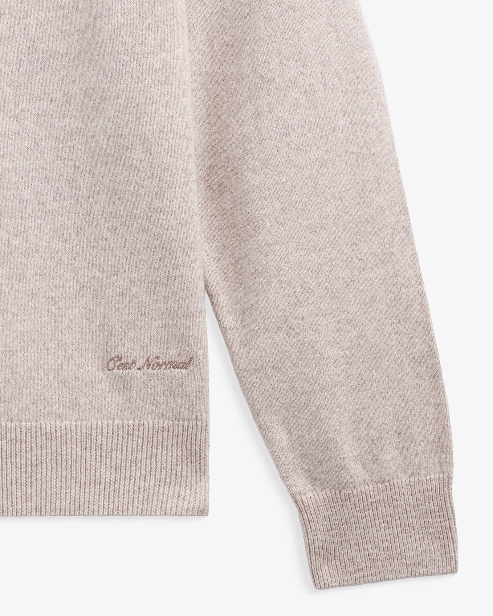 The Toulouse Hoodie in beige — close-up of embroidered C'est normal logo