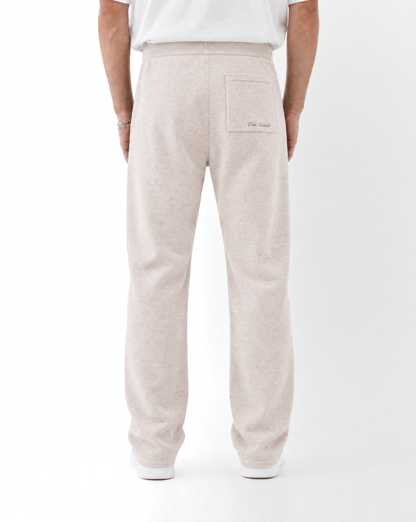 The Toulouse Pant in beige — back view with embroidered logo on rear pocket