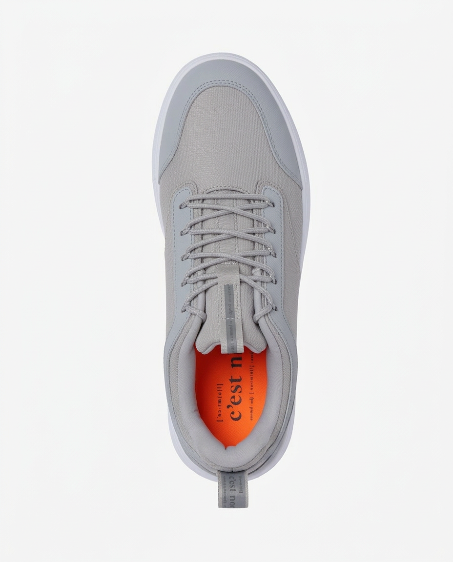 A top-down view of The Dynamic Waterproof Sneaker 2.0 Low in grey, laid flat on a white background. The image highlights the waterproof upper, laces, padded collar, and the bright orange insole featuring the c'est normal logo.