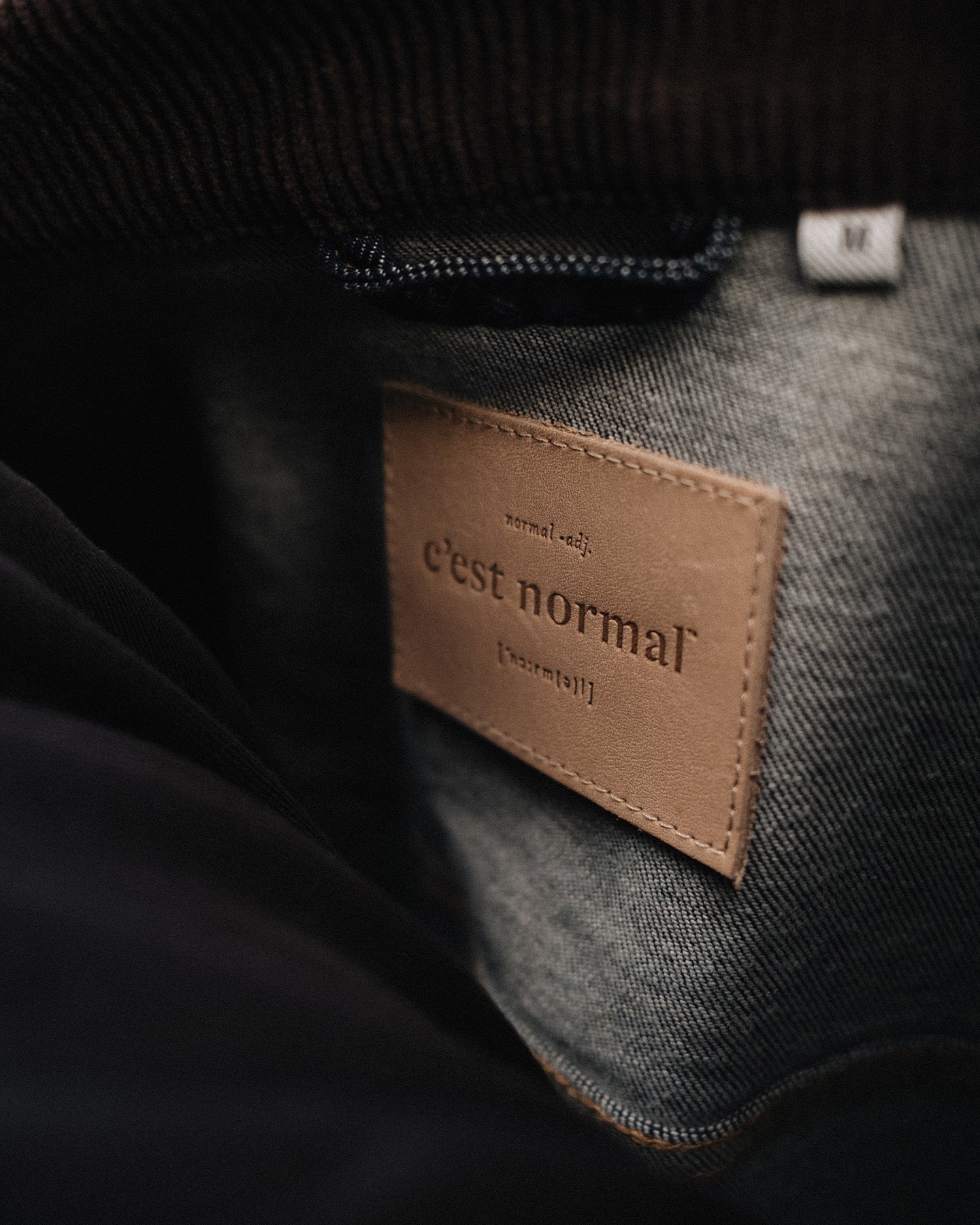 The Denim Jacket in rinse — close-up of the C'est normal neck label