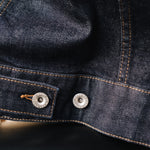 The Denim Jacket in rinse wash — close-up of the adjustable waist strap and silver buttons