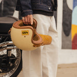 The Jeans Relaxed Straight Fit in ecru — worn while holding a motorcycle helmet