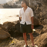 The Holiday Linen SS Shirt in off white — worn on a rocky coast at sunset