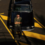 The Holiday Linen SS Shirt in dark khaki — worn while leaning against a vintage black car