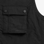 The Utility Vest in black — close-up of chest pocket with snap buttons and C'est normal branding