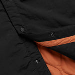 The Utility Vest in black — close-up showing the orange quilted lining and snap buttons