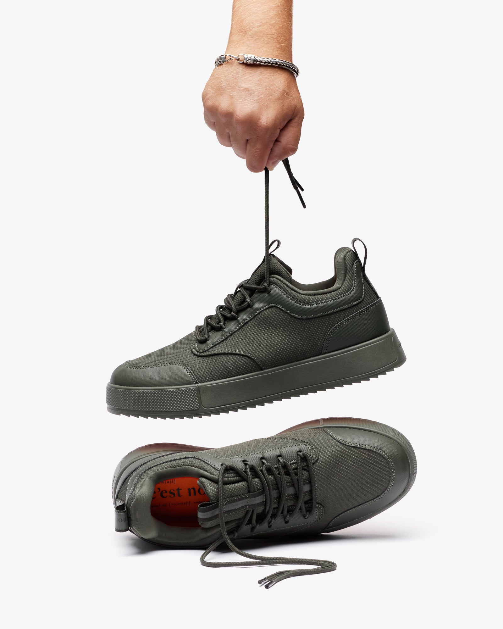 The Dynamic Waterproof Sneaker 2.0 Low in khaki — held up by the laces showing the waterproof upper and orange insole